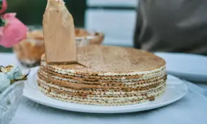 Nakładanie kremu na ciasto na gofrach bez pieczenia. Warstwy wafli przełożone pysznym, karmelowym nadzieniem.