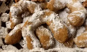 Pyszne ciasteczka orzechowe księżyce, posypane cukrem pudrem, leżą w koszyku wyłożonym koronką.