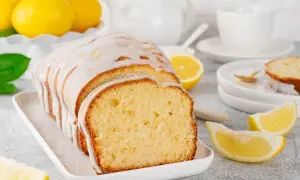 Pyszne ciasto cytrynowa fantazja, polane lukrem, z kawałkami cytryny w tle. Idealne na popołudniową herbatę.