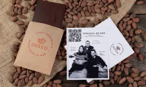 Czekolada DESEO, od ziarna do tabliczki (bean to bar), otoczona ziarnami kakaowca. Obok opakowanie i ulotka z QR kodem.