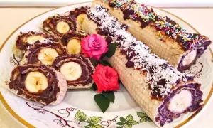 Rolada waflowa z galaretką i bananem, posypana wiórkami kokosowymi i kolorową posypką.