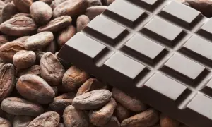 Czekolada, co to znaczy? To smak kakao i słodycz. Na zdjęciu tabliczka ciemnej czekolady wśród ziaren kakaowca.