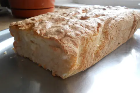 Puszyste ciasto z białek i kokosu, lekko zarumienione, na metalowej tacy.