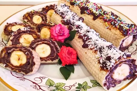 Rolada waflowa z galaretką i bananem, posypana wiórkami kokosowymi i kolorową posypką.