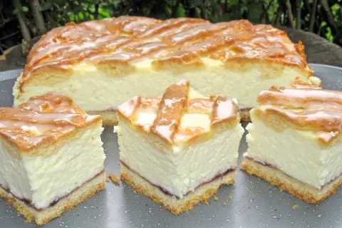 Pyszny sernik z dżemem, polany lukrem, pokrojony na kawałki. Idealny na deser.