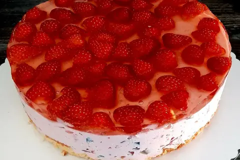 Pyszne ciasto kryształek bez pieczenia, obficie udekorowane świeżymi truskawkami w galaretce. Idealne na letnie popołudnie.