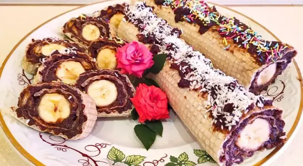 Rolada waflowa z galaretką i bananem, posypana wiórkami kokosowymi i kolorową posypką.