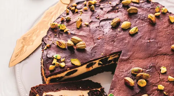 Pyszne ciasto serowe ze śliwkami, polane czekoladą i posypane pistacjami. Idealne na deser!