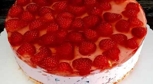 Pyszne ciasto kryształek bez pieczenia, obficie udekorowane świeżymi truskawkami w galaretce. Idealne na letnie popołudnie.