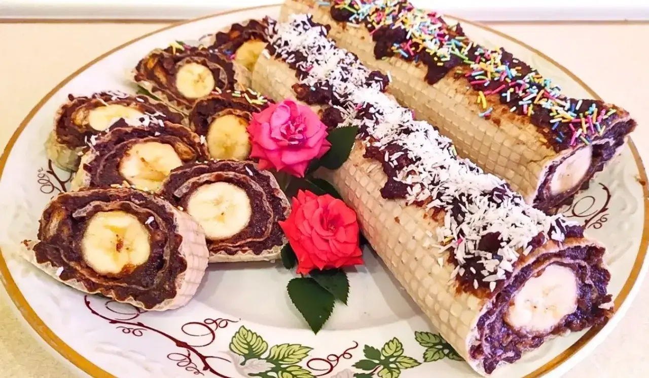 Rolada waflowa z galaretką i bananem, posypana wiórkami kokosowymi i kolorową posypką.