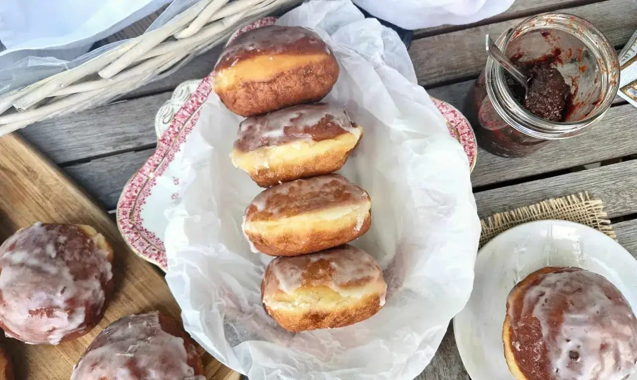 Pączki z piwem, lukrowane i rumiane, czekają na talerzyku. Obok słoiczek z konfiturą.