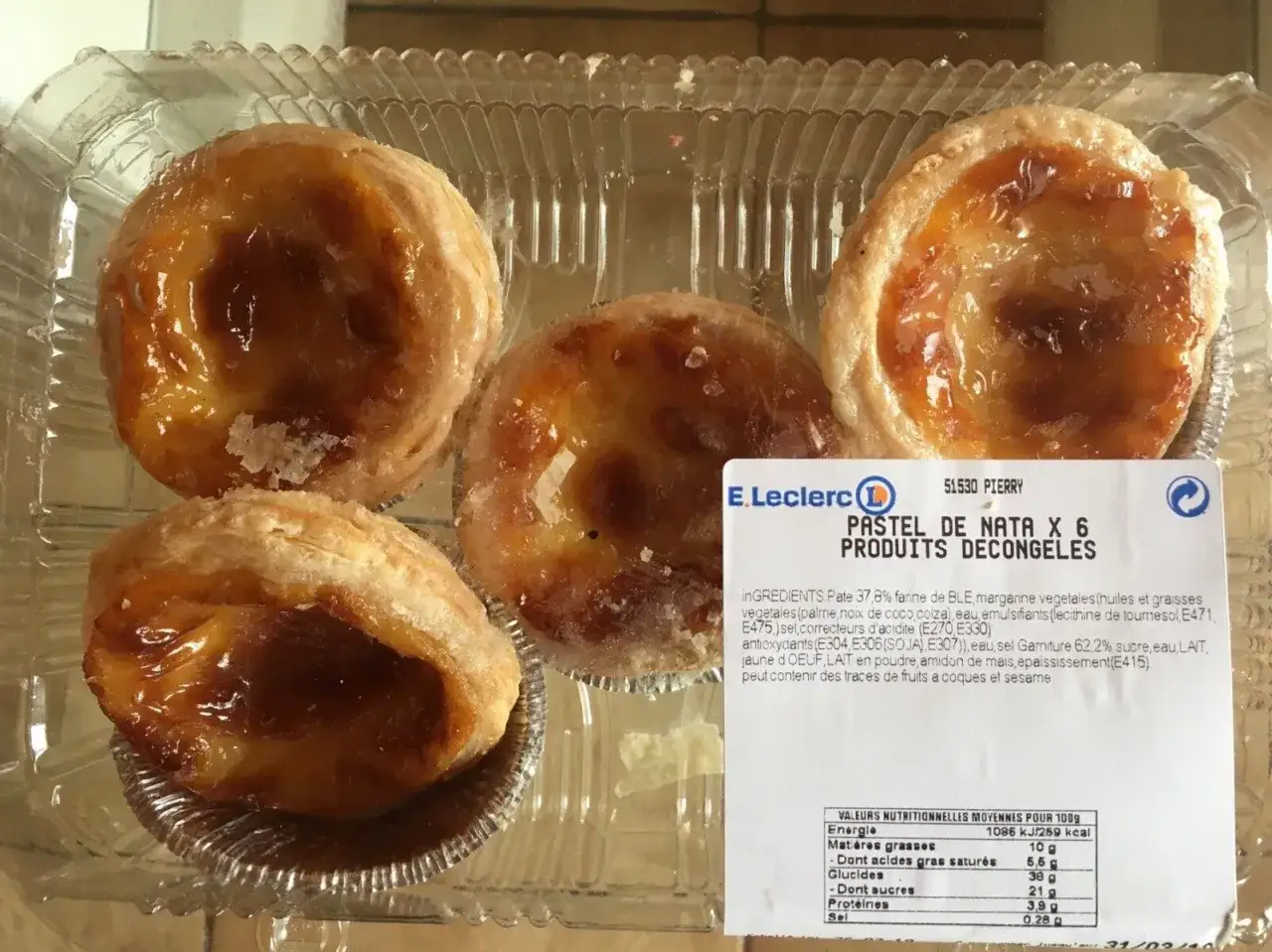 Cztery pyszne babeczki Pastel de Nata w plastikowym opakowaniu. Na etykiecie widnieje informacja o wartościach odżywczych, w tym pasteis de nata kcal.