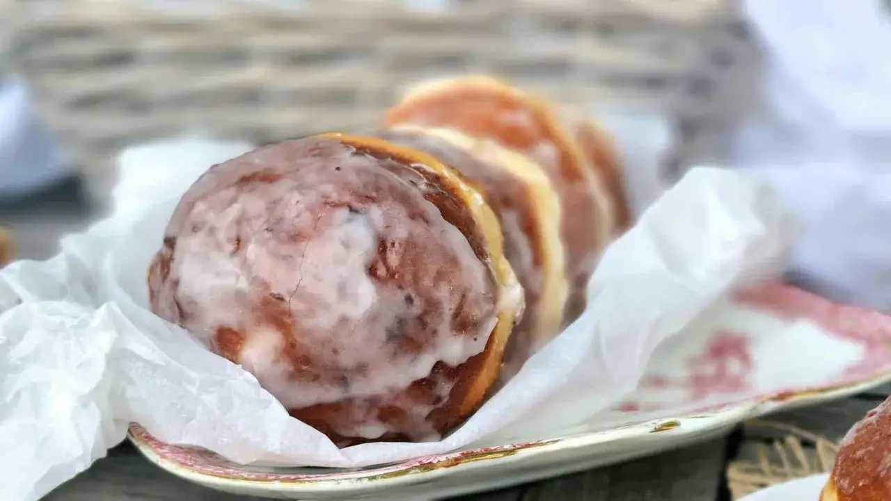 Pyszne pączki z piwem, oblane lukrem, ułożone na talerzyku z papierową serwetką.