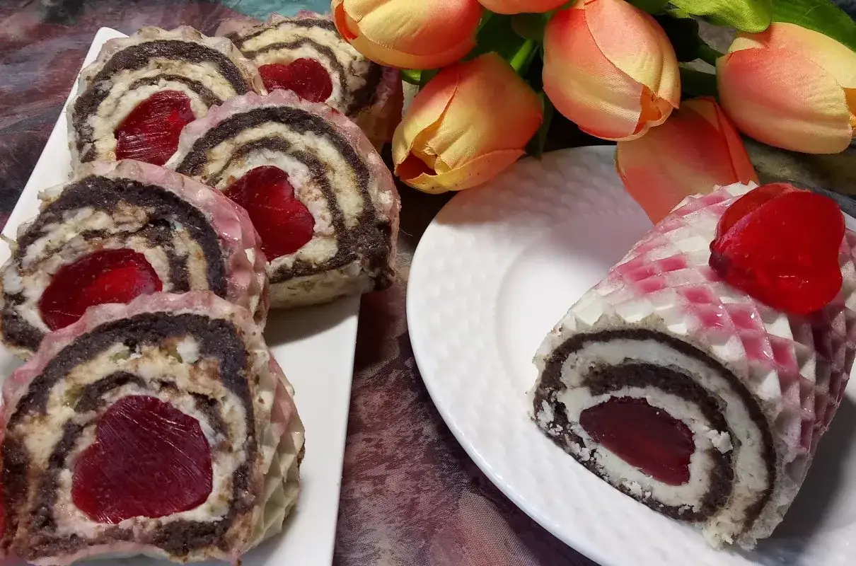 Rolada waflowa z bakaliami i galaretką w kształcie serca, ozdobiona tulipanami.