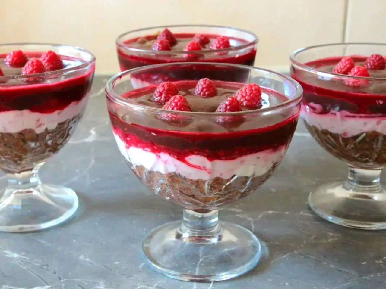 Deser w pucharkach z warstwami ciastek, kremu i malinową polewą z serka mascarpone.