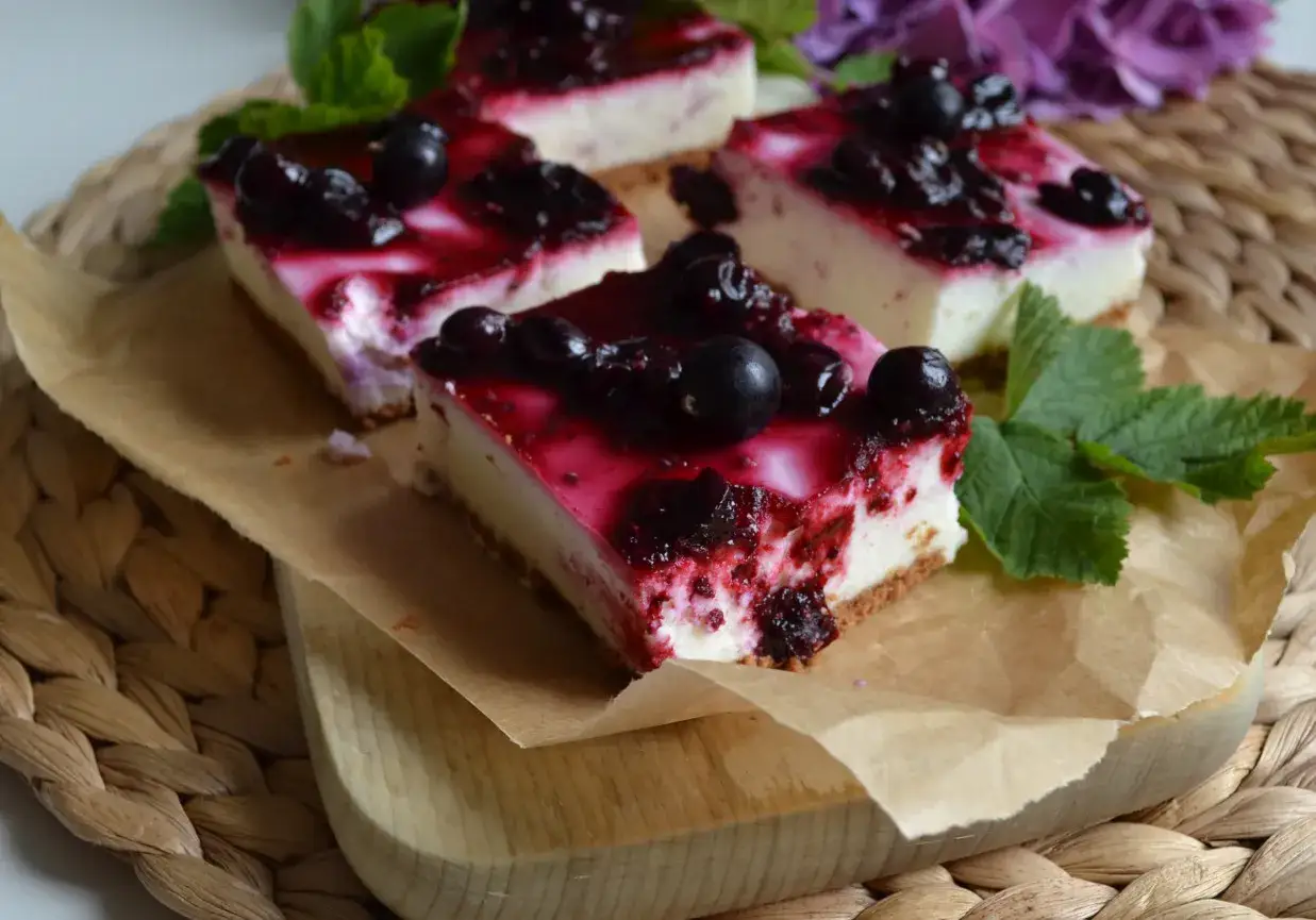 Pyszny porzeczkowiec na herbatnikach, udekorowany świeżymi porzeczkami i listkami mięty.