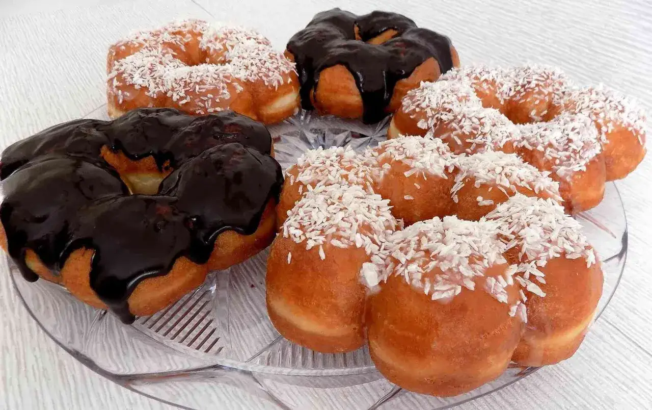 Pączki z piwem, niektóre oblane czekoladą, inne posypane wiórkami kokosowymi, kuszą na talerzu.